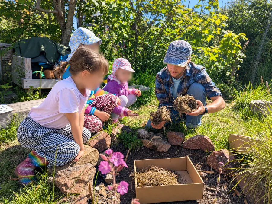 Ross showing young children a bird’s nest beside a box of nesting materials